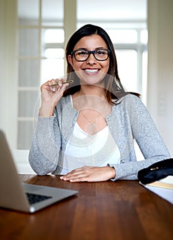 Woman sitting upright smiling at home office desk.