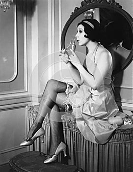 Woman sitting on a vanity smelling perfume from flacon photo