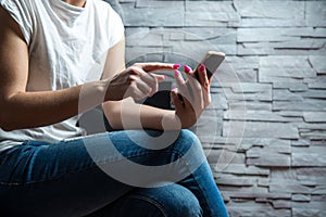 Woman sitting at the wall and browsing the phone.