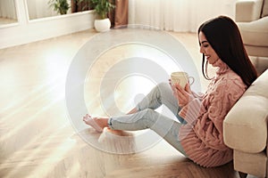 Woman sitting on warm floor in living room. Heating system