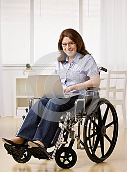 Woman sitting in wheel chair typing on laptop