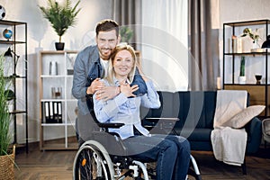 Woman sitting in wheelchair while husband hugging her behind