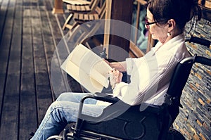 A woman sitting on a wheelchair and reading