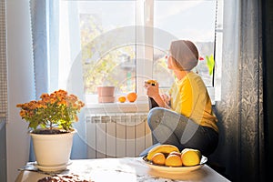 Woman sitting by the window and drinking tea. Side view