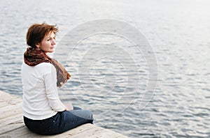 Woman sitting on wood boards by the water