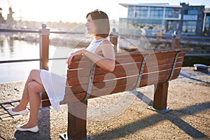 Woman sitting on a wooden bench enjoying the warm sunlight