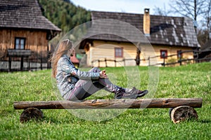 Žena sedící na dřevěné lavici před venkovskou obcí Vlkolínec na Slovensku