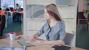 Woman sitting at the working place works with laptop than close it and relax with drink