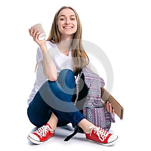 Woman sitting writing in notebook with pen backpack drink cardboard cup of coffee