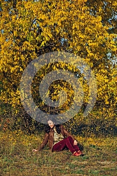 Woman sitting on a yellow autumn leaves backgrounds