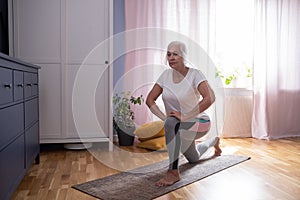 woman sitting on the yoga mat and stretching her legs in the living room. photo