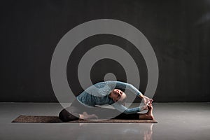 Woman sitting in yoga pose Parivrtta Janu Sirsasana