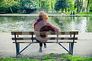 Woman sittng on bench by a pond in the park