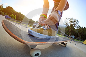 Woman skateboard tying shoelace at skatepark