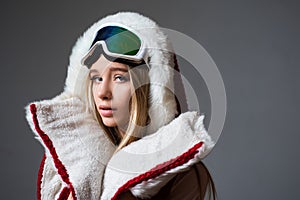 Woman in ski clothing poses with a ski goggles. Portrait of young girl with snow goggles.