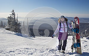 A woman in ski equipment is standing on the top of a mountain. A girl at a ski resort