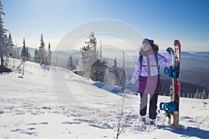 A woman in ski equipment is standing on the top of a mountain. A girl at a ski resort