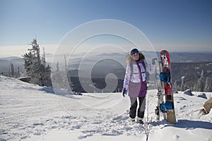 A woman in ski equipment is standing on the top of a mountain. A girl at a ski resort