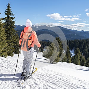 Woman ski tourist on snow slope looking at winter mountain. Ski resort Pamporovo, Bulgaria. Girl skier with backpack
