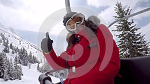 Woman Skier Climbs On The Chair Lift To The Top Of The Mountain And Waving Hand