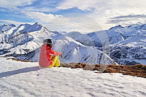 Woman skier looking at the mountain peaks in the French Alps, on Les Sybelles ski domain, above Saint-Jean-d`Arves village, France