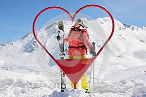 Woman skier poses inside a heart shaped frame at Tignes - Val d\'Isere ski resort, France