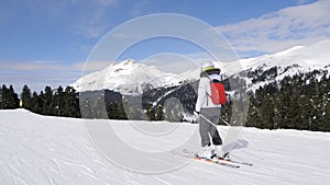 Woman Skier Slides Down Snowy Ski Slope In Mountains With Pine Trees In Winter