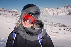 Woman skier on the slope of a mountain resort. Portrait of a young woman smiling in ski equipment, goggles and a helmet