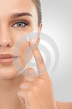 Woman, skincare and cream in studio portrait, hydration and proud of glow on white background. Female person, half face