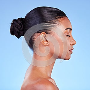 Woman, skincare and profile of natural beauty or shine on skin from cosmetics on blue background in studio with calm