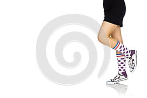 Woman in a skirt wearing transparent summer shoes and colorful sock