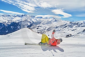 Woman on skis posing at Les Sybelles ski domain, on a blue sky sunny day, with Aguilles d Arves peak in the back.