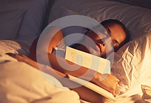 Woman, sleep and book in bed and resting, dreaming female person or night lamp for story and novel. Relax, hobby and