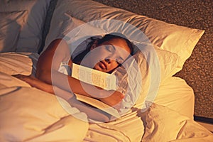 Woman, sleep and book in room and light, dreaming female person or night lamp for story and novel. Relax, hobby and
