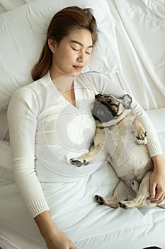 woman sleep with dog pug breed on bed in bedroom