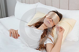 Woman with sleep mask in bed at home