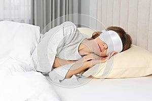 Woman with sleep mask in bed at home