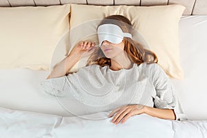 Woman with sleep mask in bed, top view