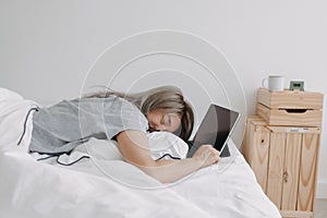 Woman sleep on tablet computer on bed in the morning. Early online work.