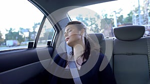 Woman sleeping on back seat taxi, exhausted after stressful workday, burnout