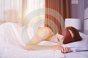 Woman sleeping on bed with eye mask in bedroom with soft light