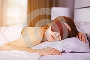 Woman sleeping on bed with eye mask in bedroom with soft light