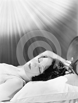 Woman sleeping in a bed with rays of light shining on her