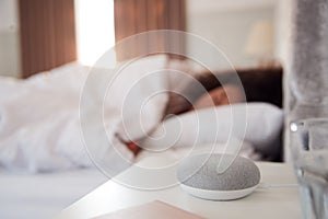 Woman Sleeping In Bed With Voice Assistant On Bedside Table Next To Her