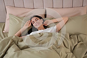 Woman sleeping in comfortable bed with green linens