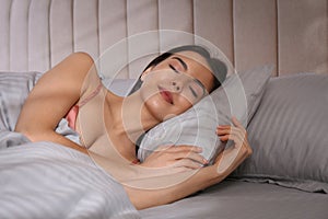 Woman sleeping in comfortable bed with grey striped linens