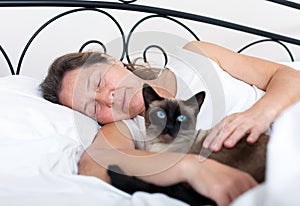 Woman sleeping in embrace with cat