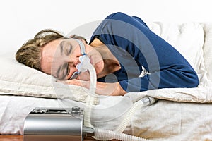 Woman sleeping on her side with CPAP machine in the foreground.