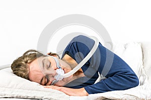 Woman sleeping on her side with CPAP, sleep apnea treatment.