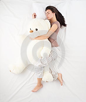 Woman sleeping with large teddy bear